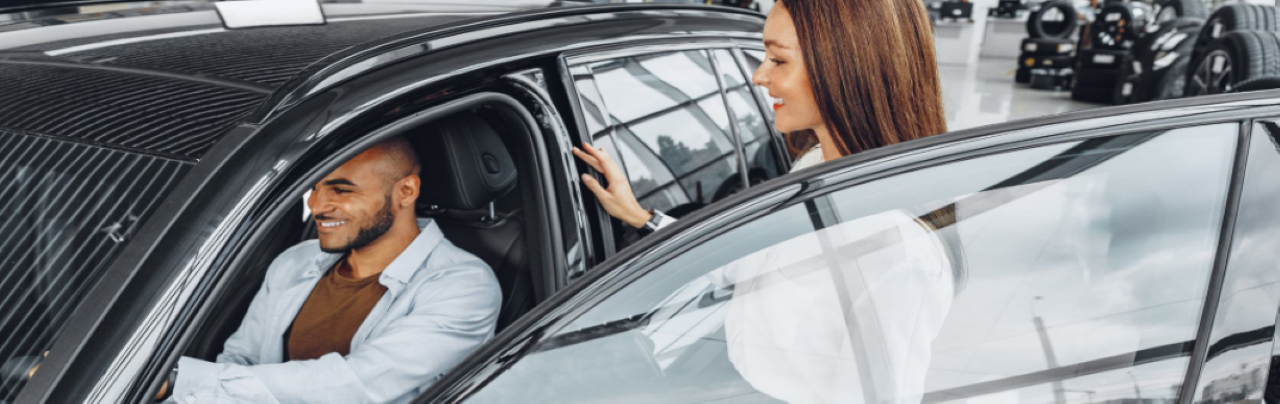 Hall's Auto Sales staff member helping a customer test drive a used car on the lot.